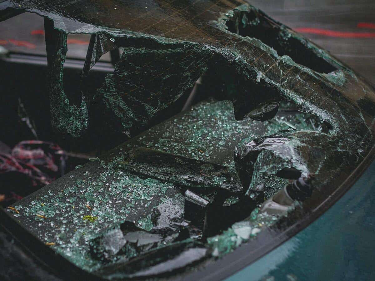 A dark green car with a shattered window after a collision. 