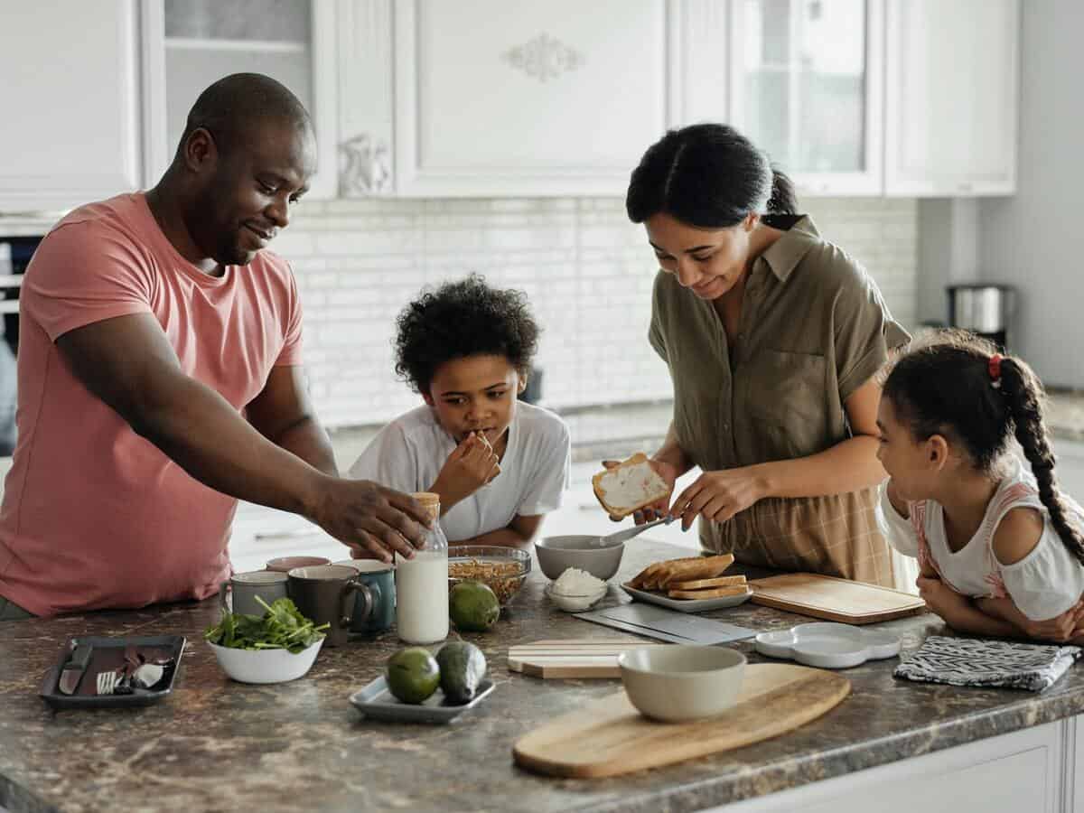 A family is gathered around a kitchen island to prepare a meal.