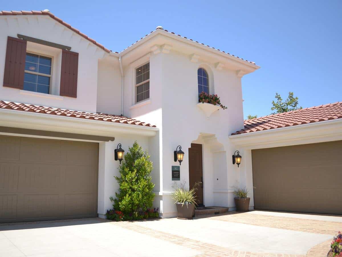 A white southwestern style home with two light brown garages.