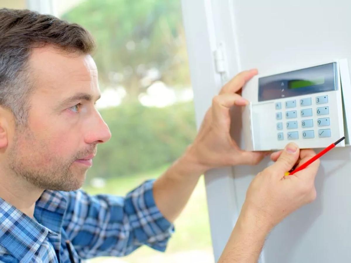 a man installing a home security system
