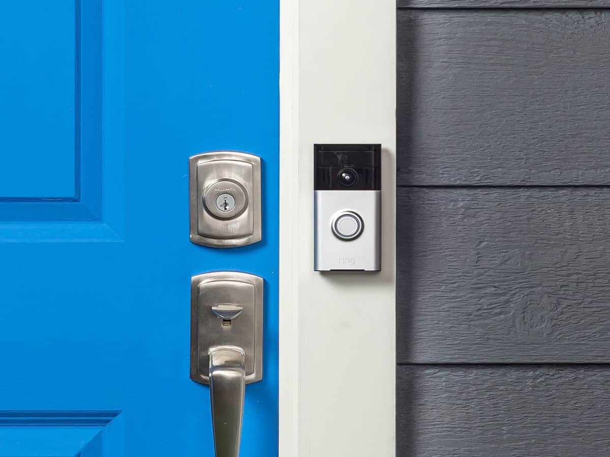A Ring doorbell camera installed next to a bright blue front door.