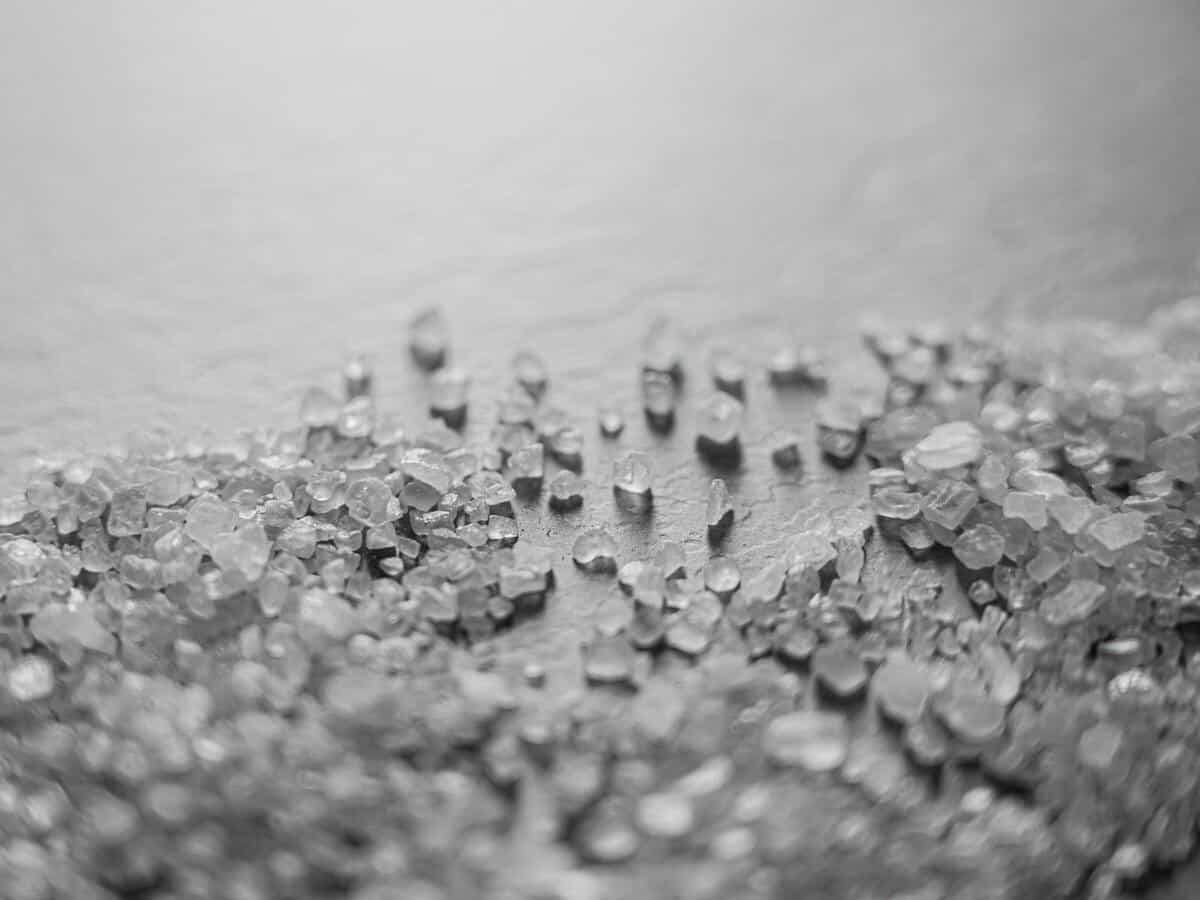 Salt crystals sitting on a brown surface.