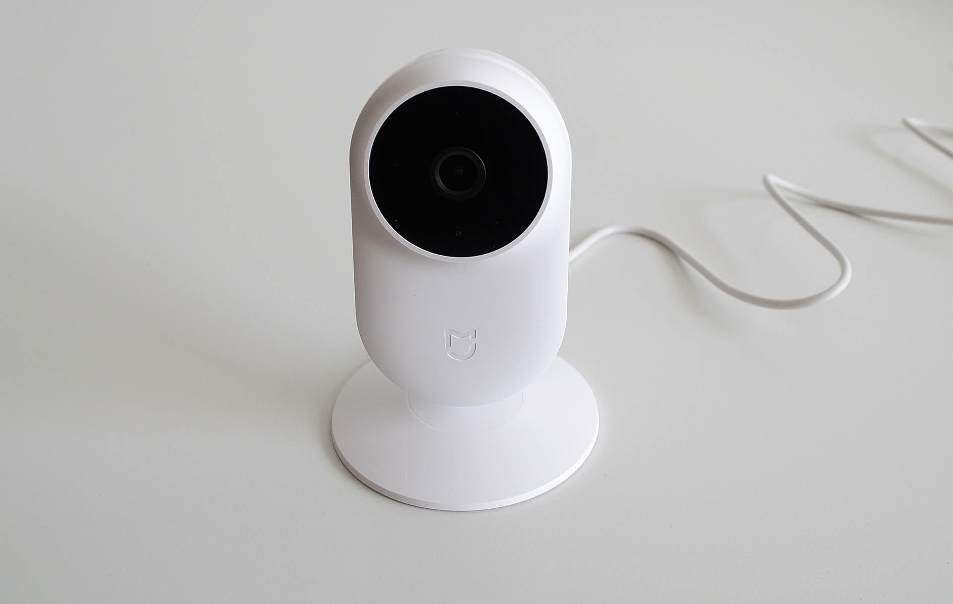 A white, compact security camera sitting on a grey surface.