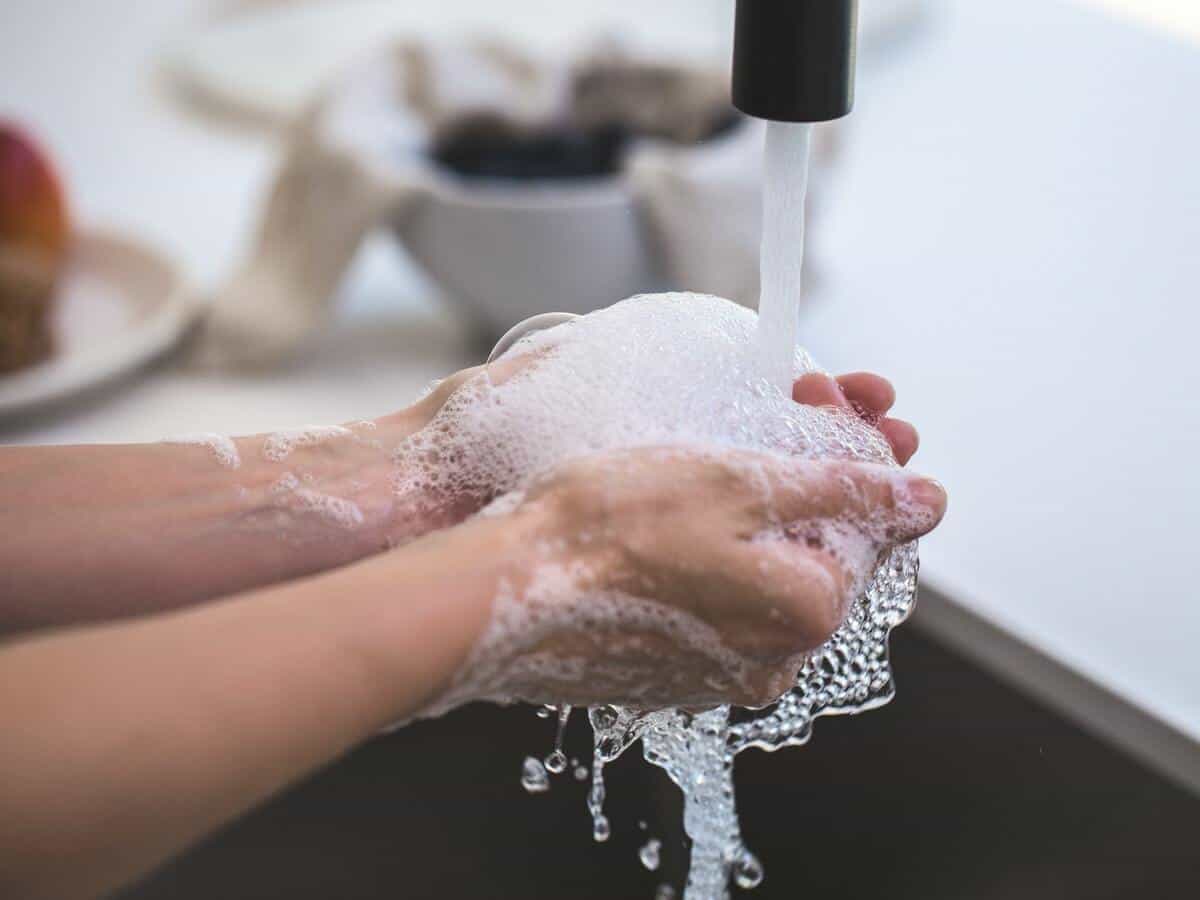 Hands with soap water over a sink.