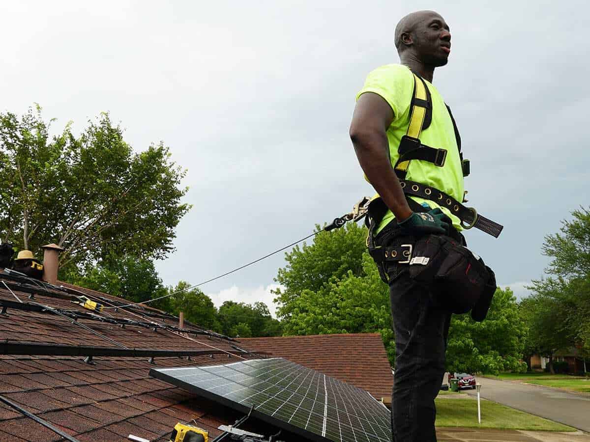 An ONIT Home Service solar panel contractor standing on a roof during installation.