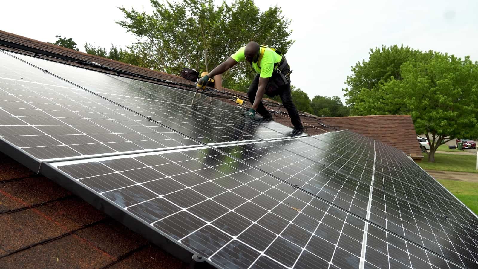 A man is installing solar panels on top of a roof.