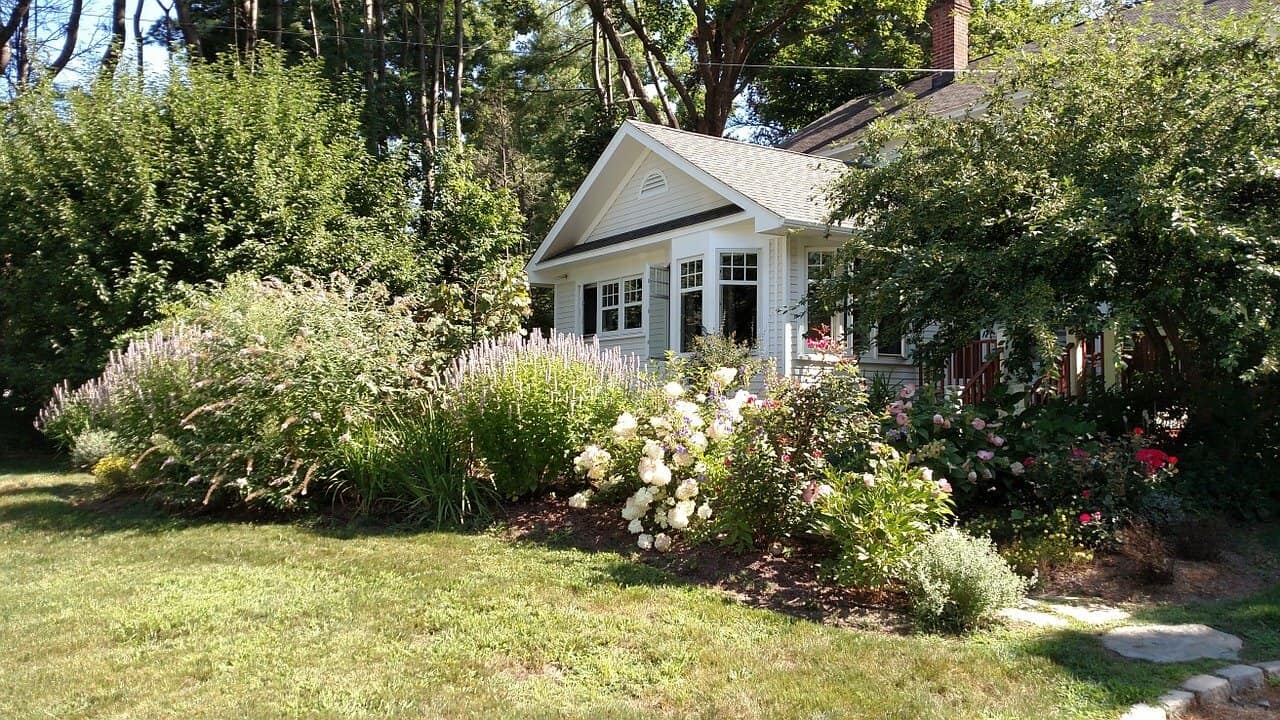 An American craftsman home surrounded by trees and beautiful floral landscaping.