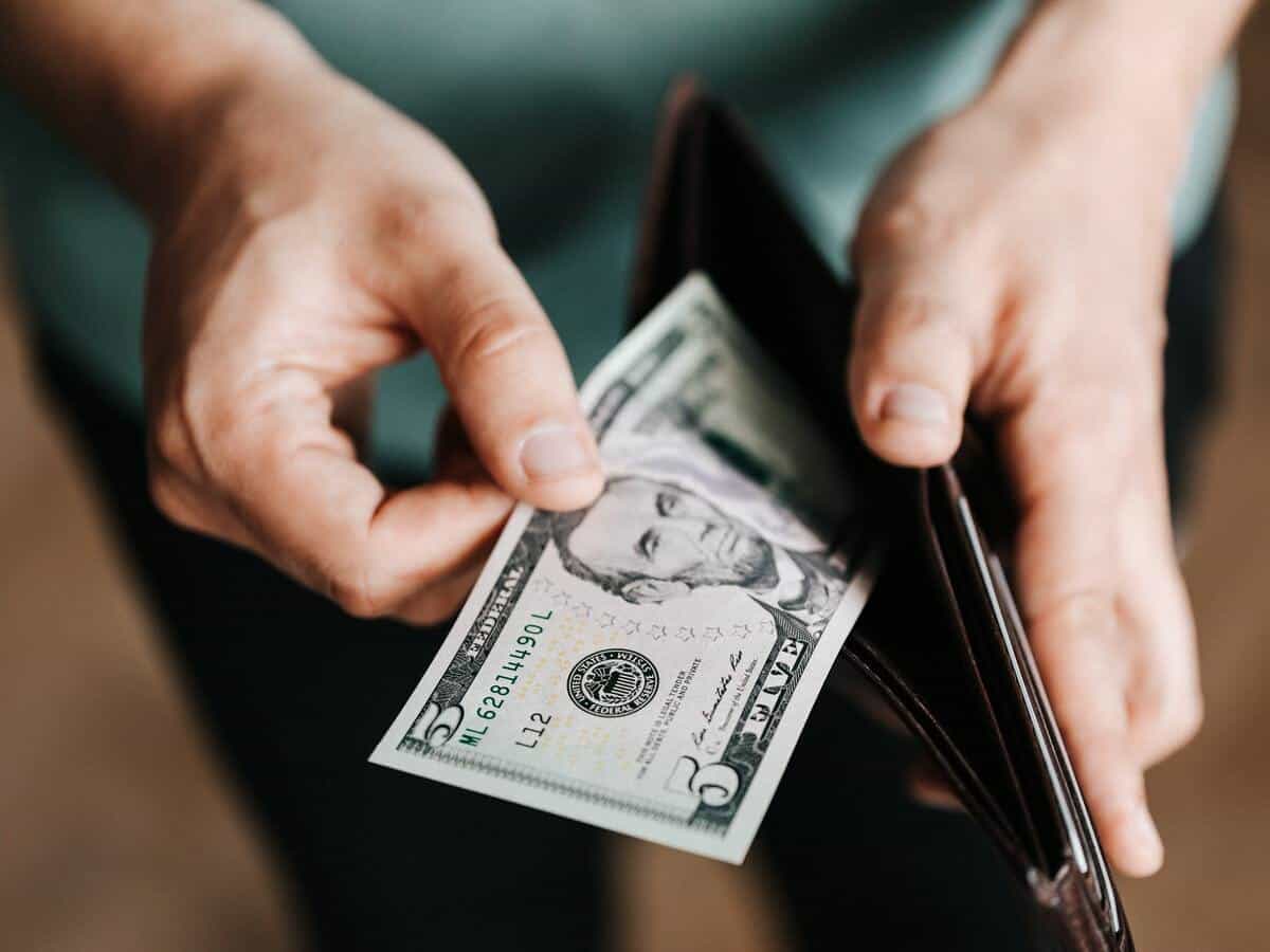 A man is pulling a five-dollar bill out of his wallet.