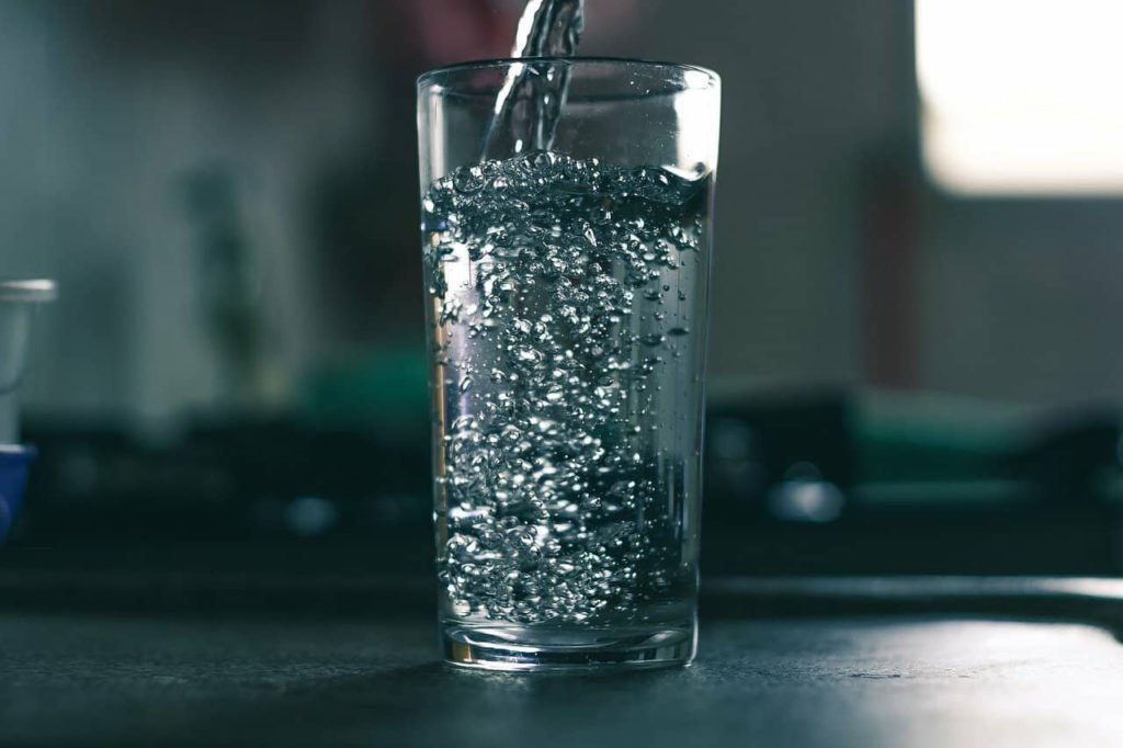 Clean water is being poured into a glass cup.