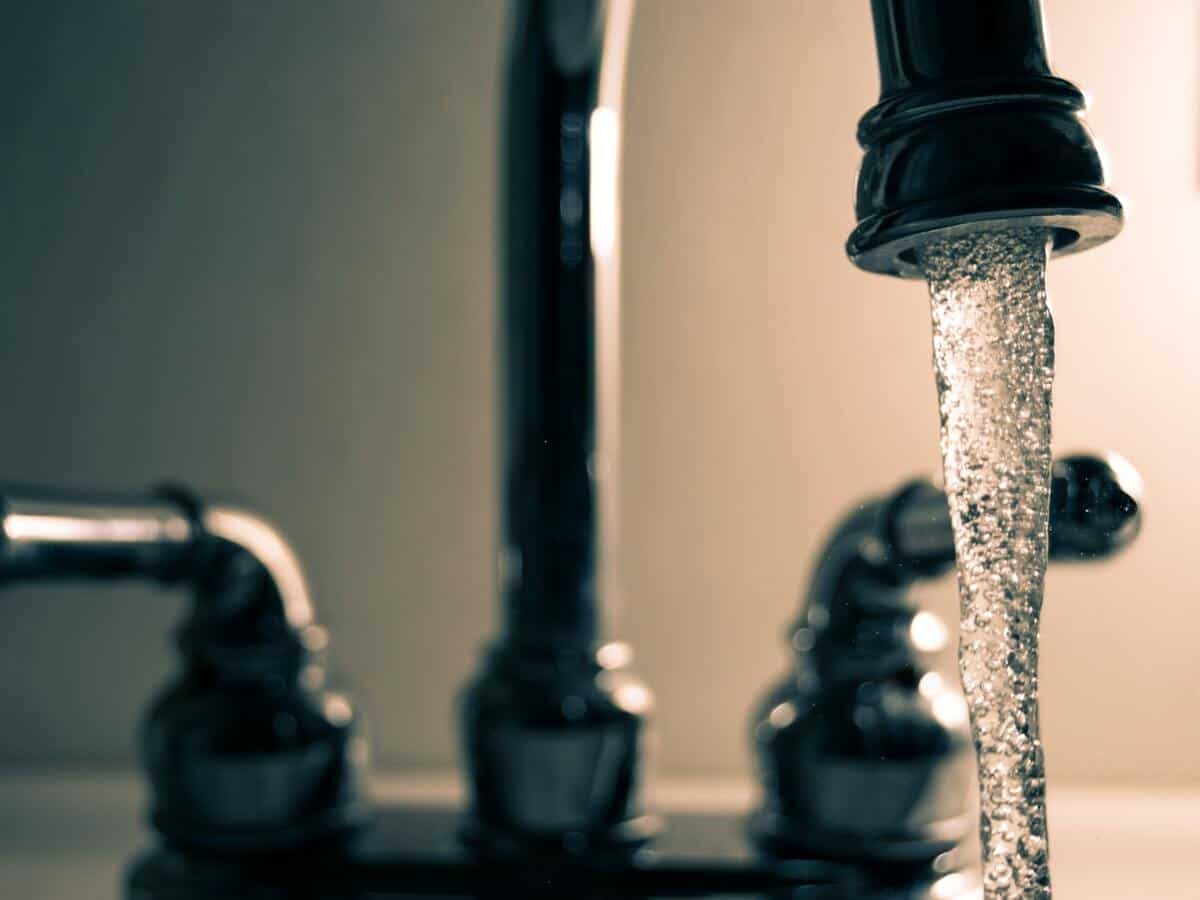 Water streaming from a metal sink faucet.