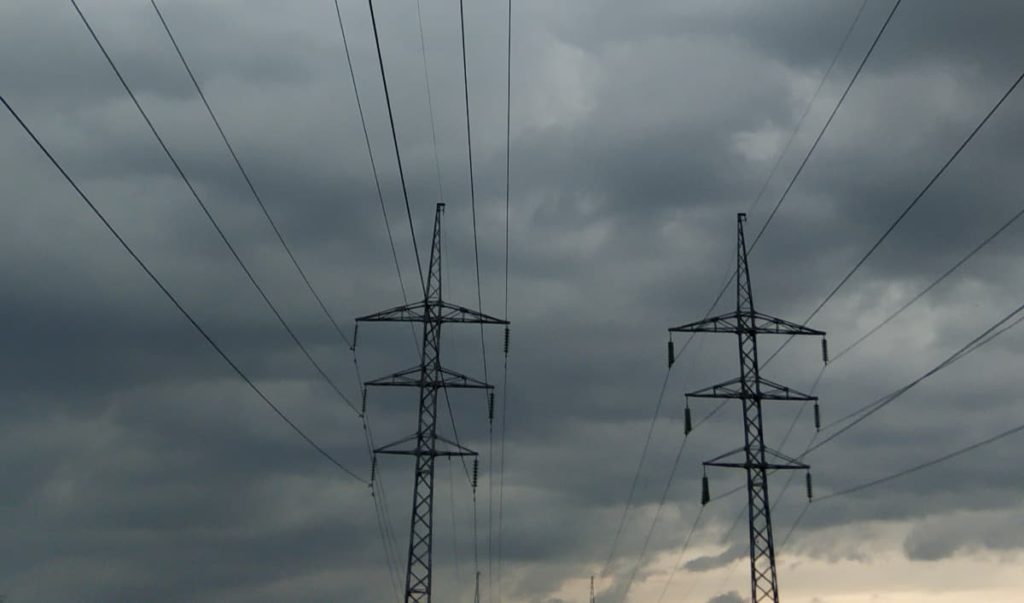 Powerlines standing up against a dark, cloudy sky.