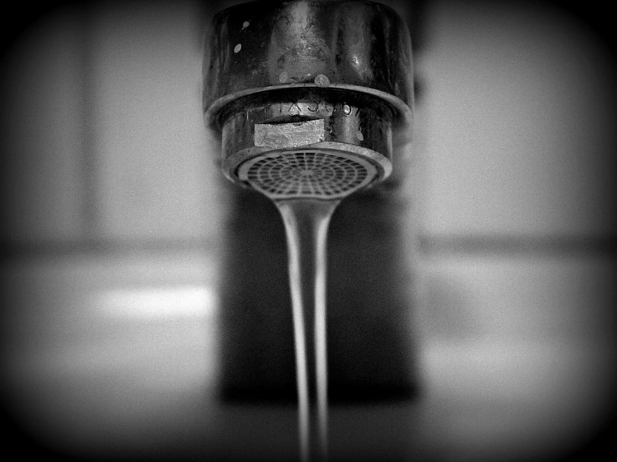 a close up of a sink faucet dripping water