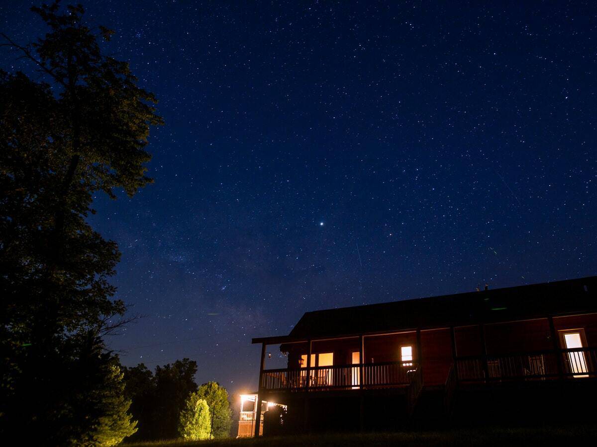 A cabin lit up with outdoor lights against a dark night sky.