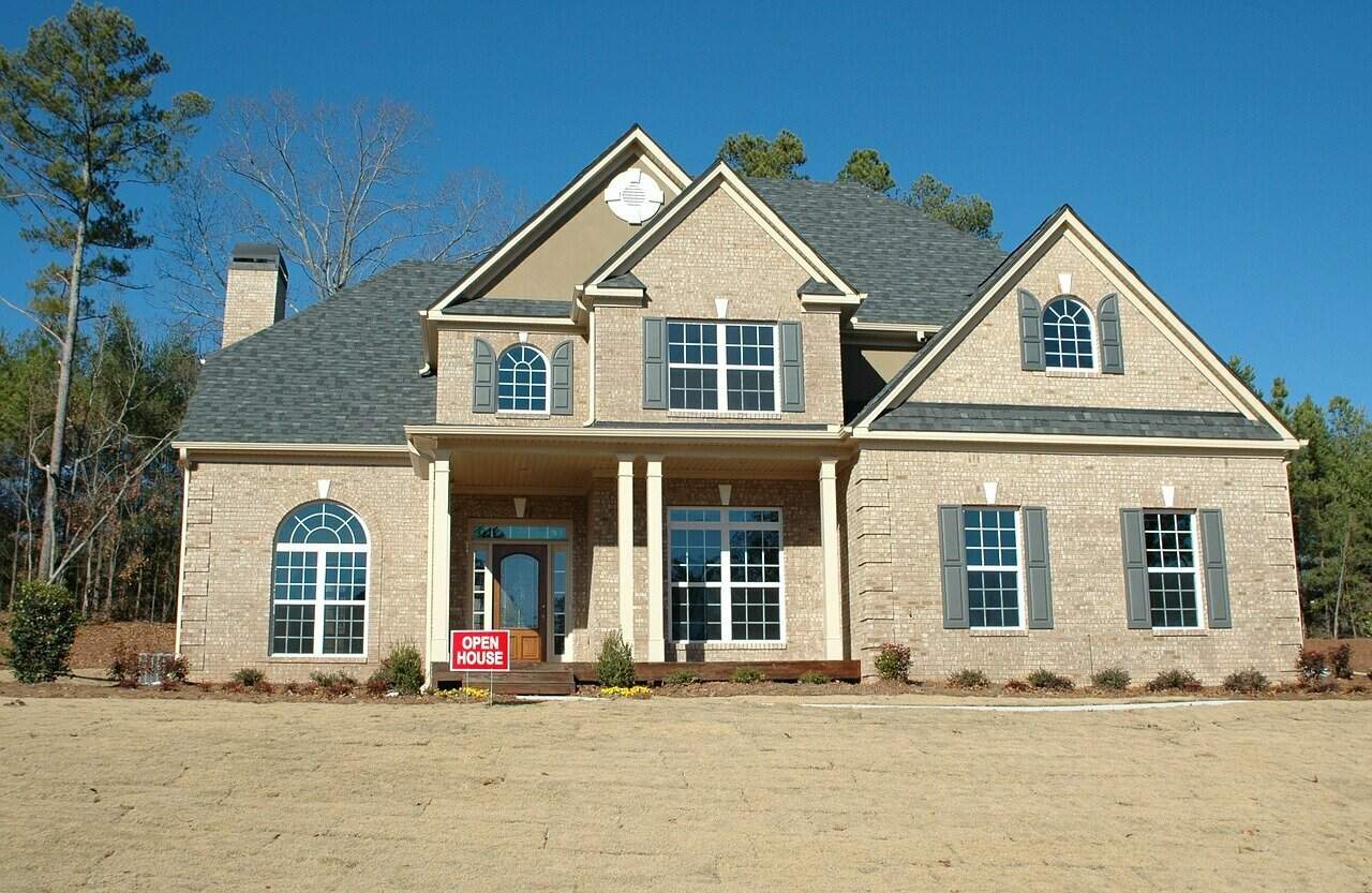 A two-story suburban home with a red "open house" sign on the front lawn.