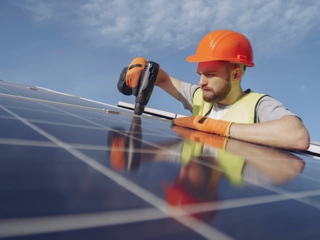 installation of solar panels guy in orange hard hat and yellow vest