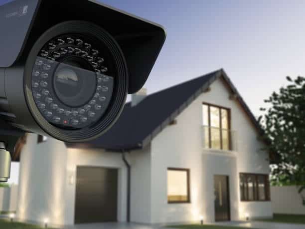 home security camera on left, white house with large windows on right side