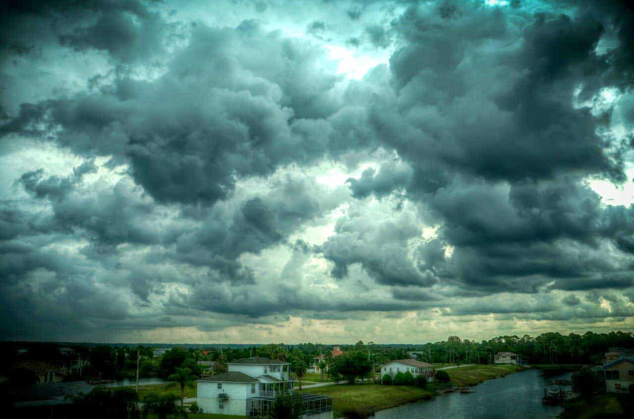 Dark and cloudy weather approaches a neighborhood in a tropical setting.