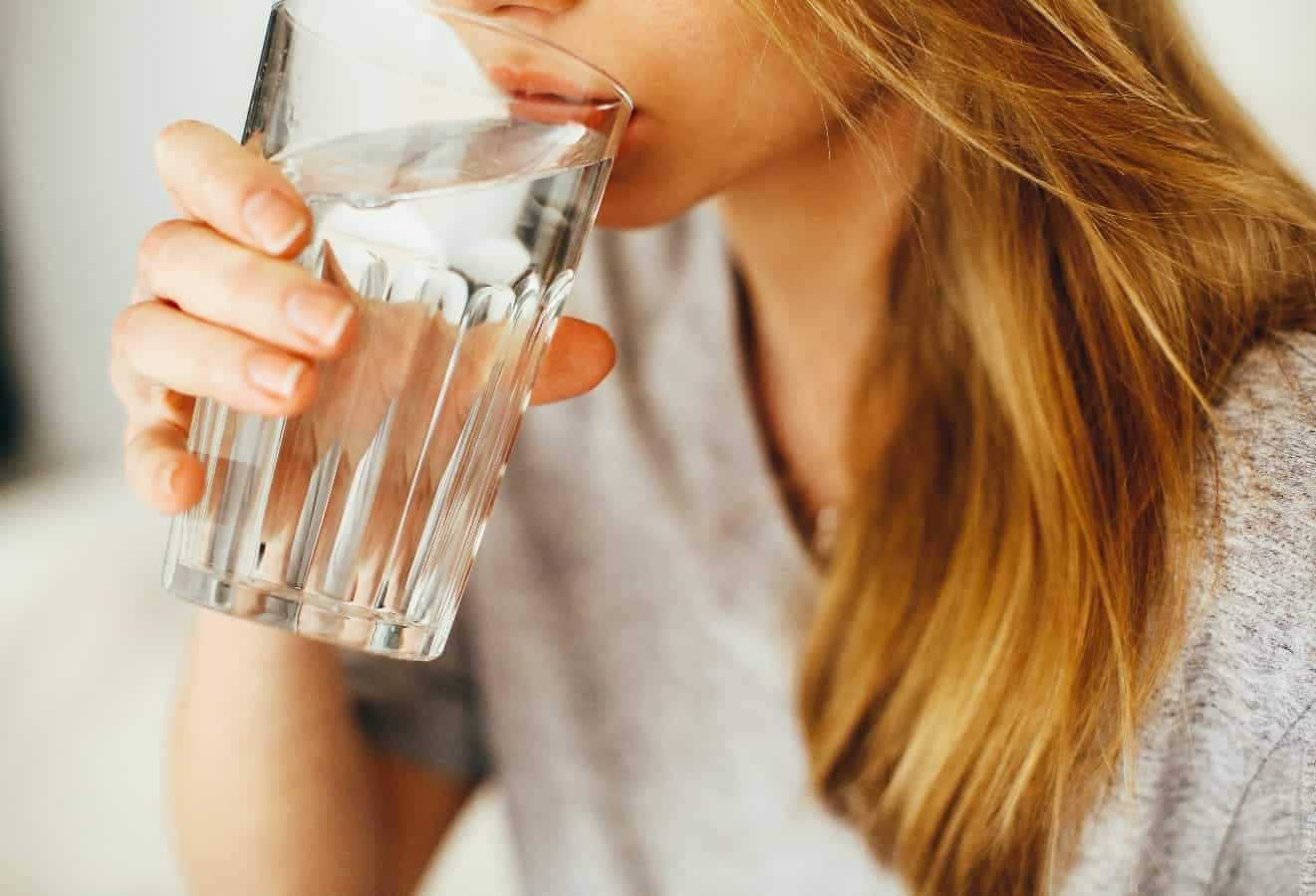 girl in gray shirt drinking out of glass