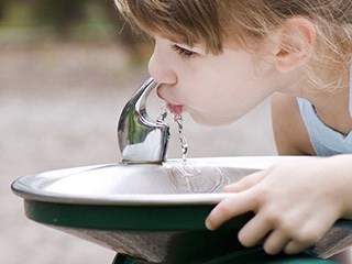 little girl drinking out of water fountain