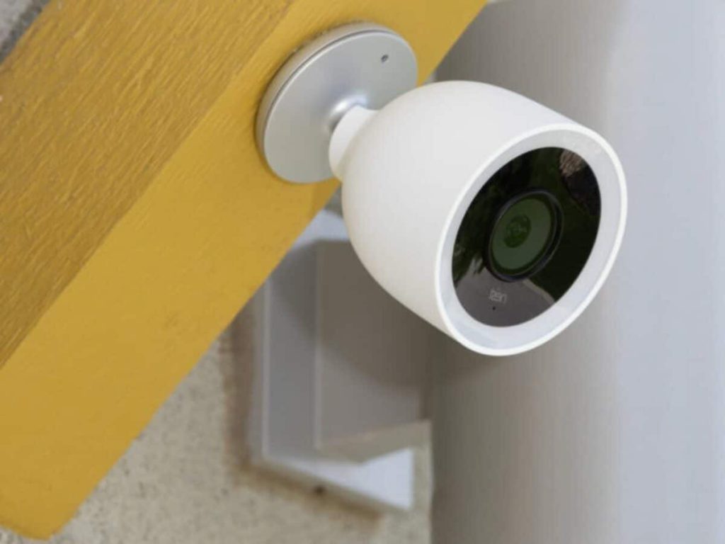 white security camera pointed left mounted on yellow wall