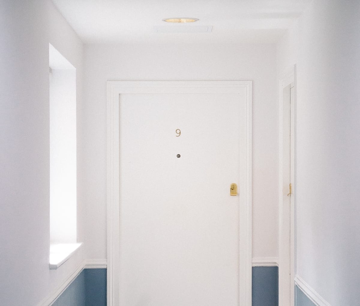 Hallway view of the front door to an apartment building with a gold number 9 on it.