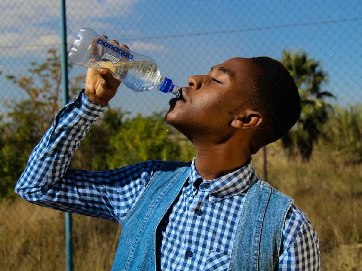 young man facing left and drinking bottled water in nice clothing