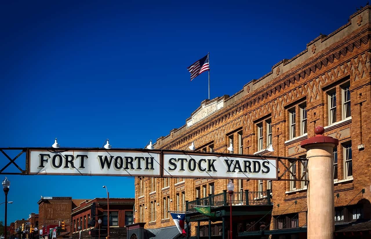 Historical buildings holding up a banner reading “Fort Worth Stock Yards”.