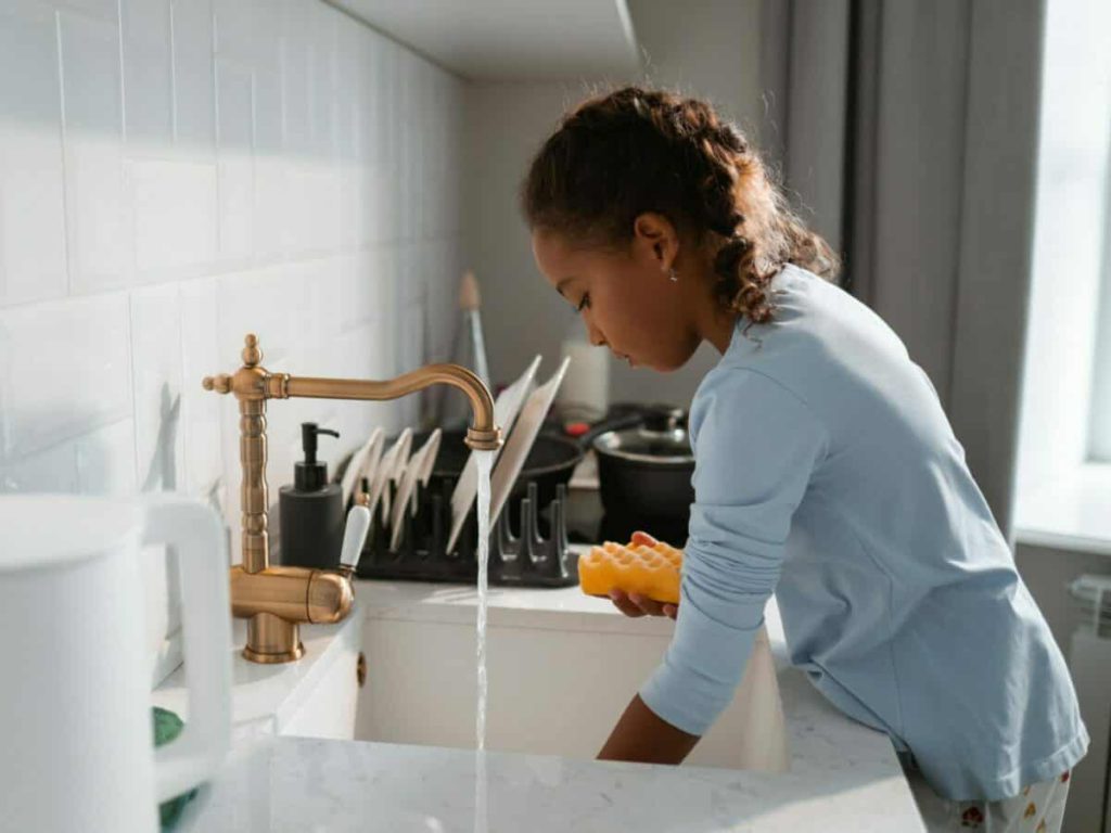 young girl in blue shirt doing dishes