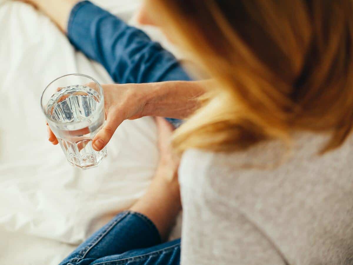 over the shoulder shot of woman drinking water in blue jeans