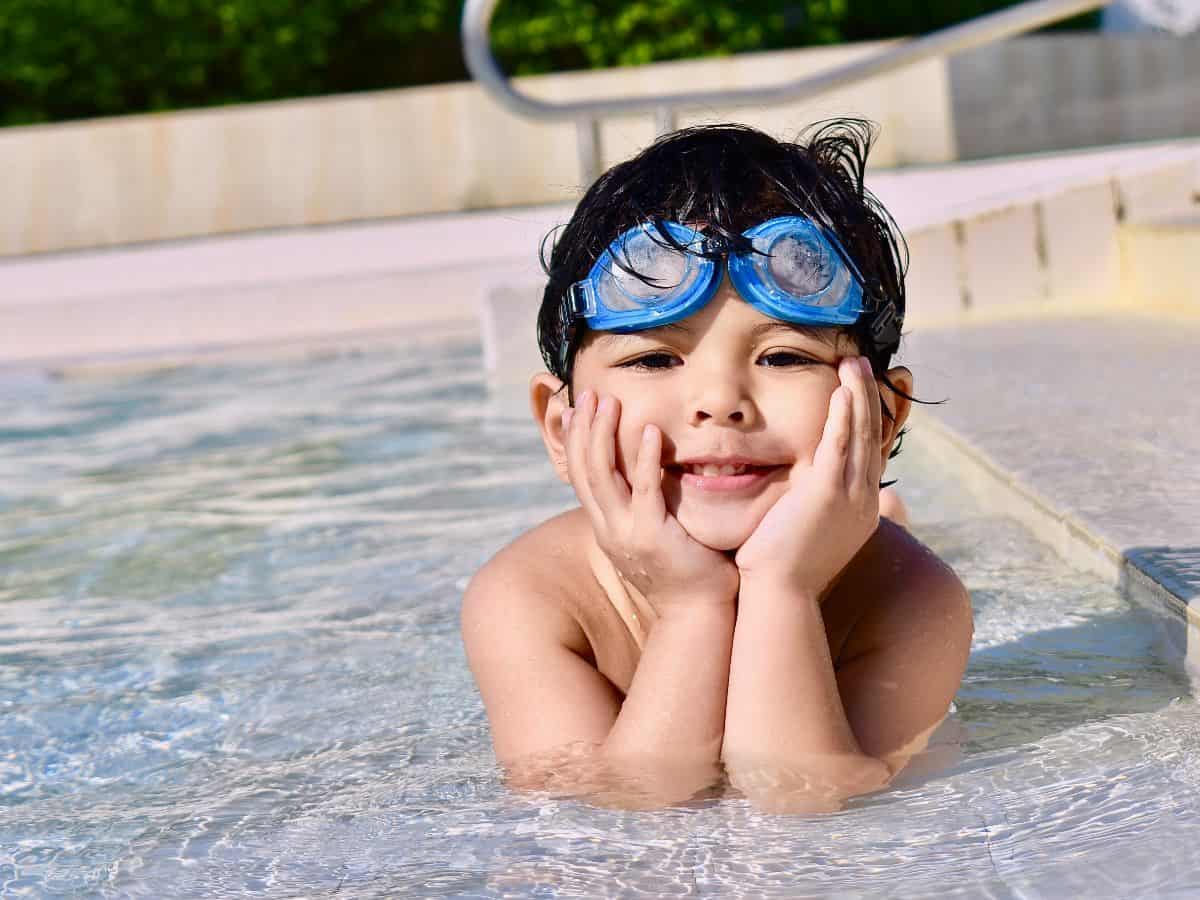 kid in pool with blue goggles