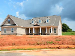 A new home with ongoing construction occurring on the exterior and front yard.