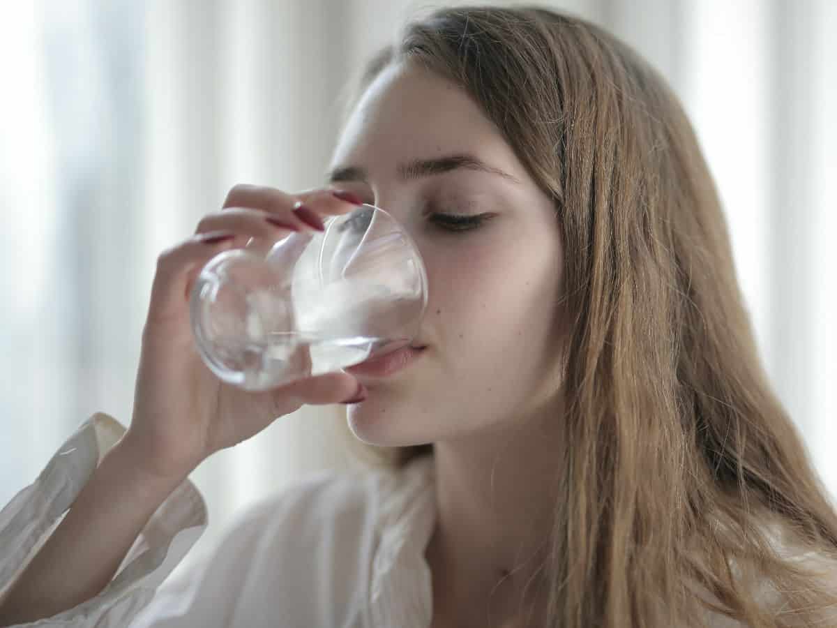 blonde drinking water out of clear glass, side angle