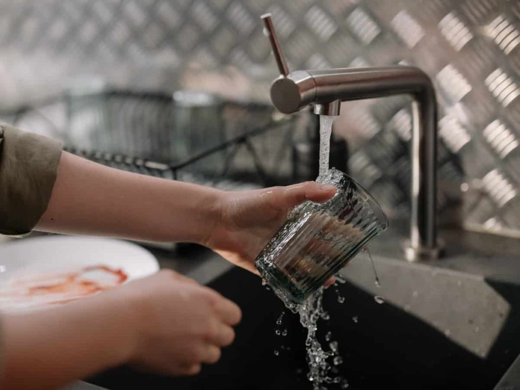 washing a glass under a faucet