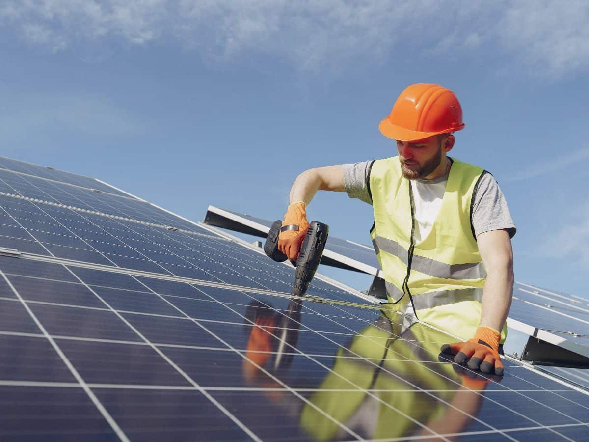 man in orange hard hat installing solar panels