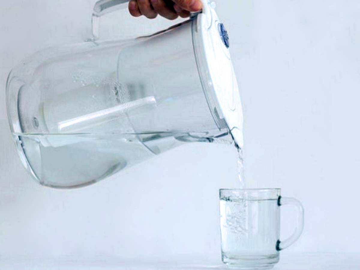 pouring filtered water into a glass, white pitcher, white background