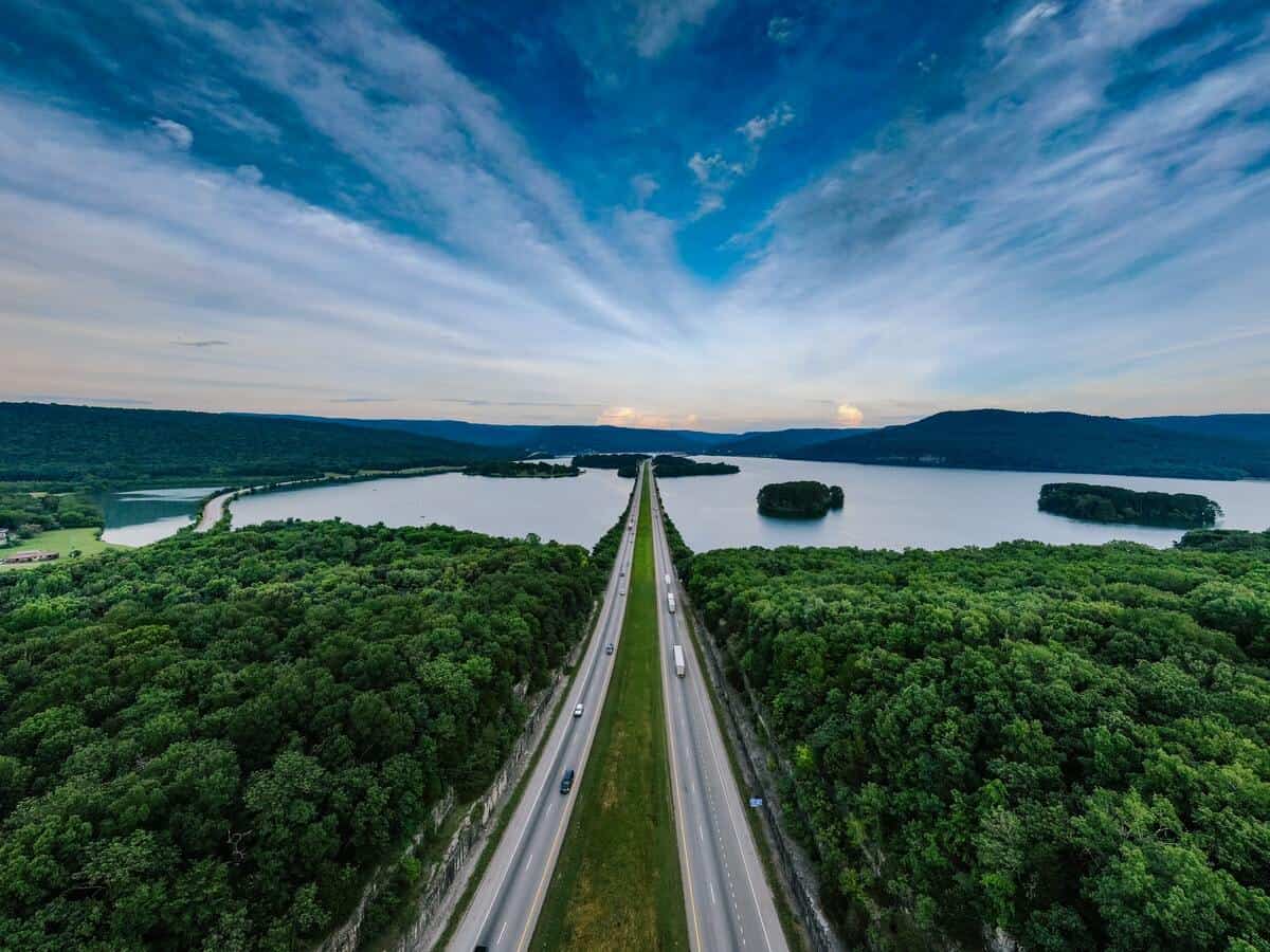 A city’s reservoir underneath an overpass surrounded by trees.