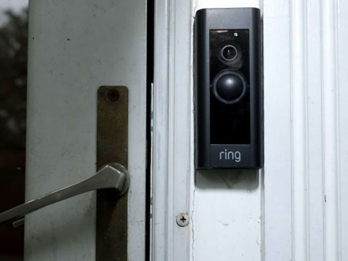 closeup of the ring doorbell camera on white siding with door handle in background