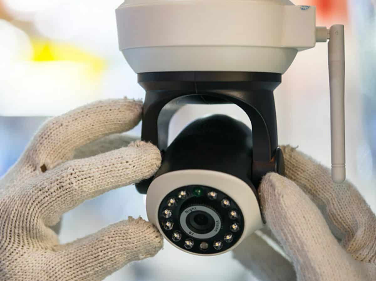 two gloved hands installing security camera