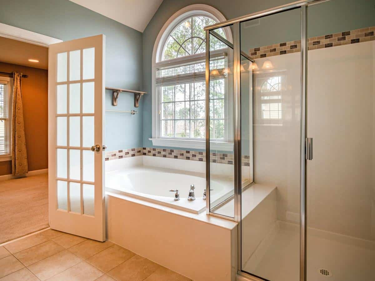 A bathroom with a deep white tub and a shower with glass doors directly beside it.