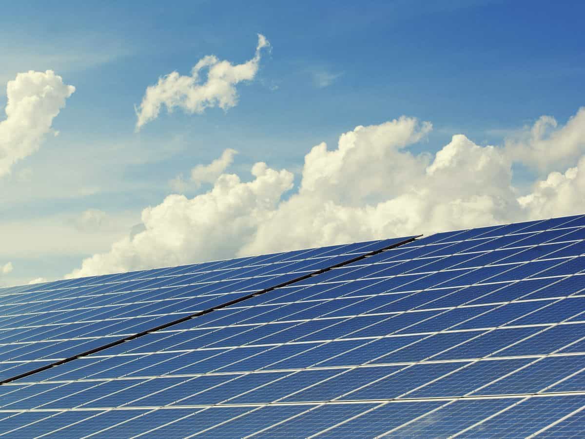 solar panels with blue, cloudy sky in the background