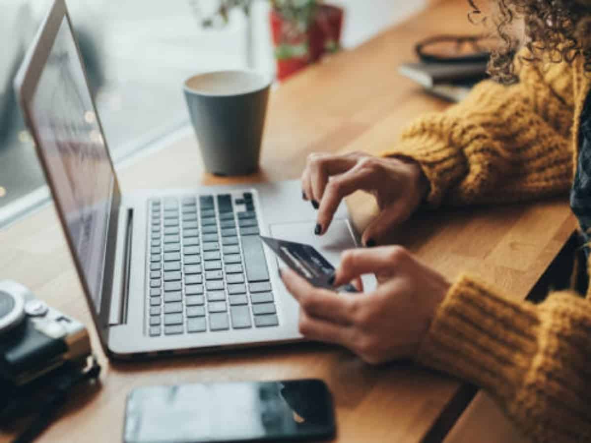 woman in yellow sweater online shopping credit card out