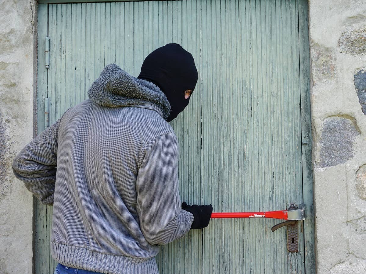 burglar in gray sweatshirt and black ski mask trying to enter door