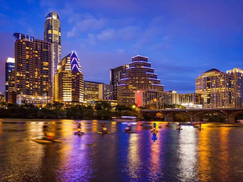 Austin, Texas downtown skyline at night on the Colorado River as unidentified tourists ride water bikes