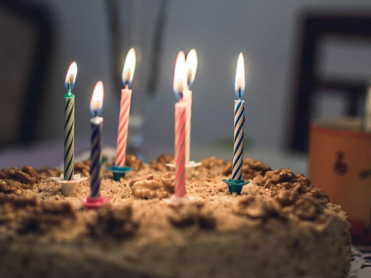 A birthday cake with six colorful glowing candles on a cake.