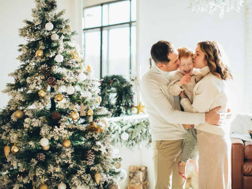 family in front of christmas tree with window in the background