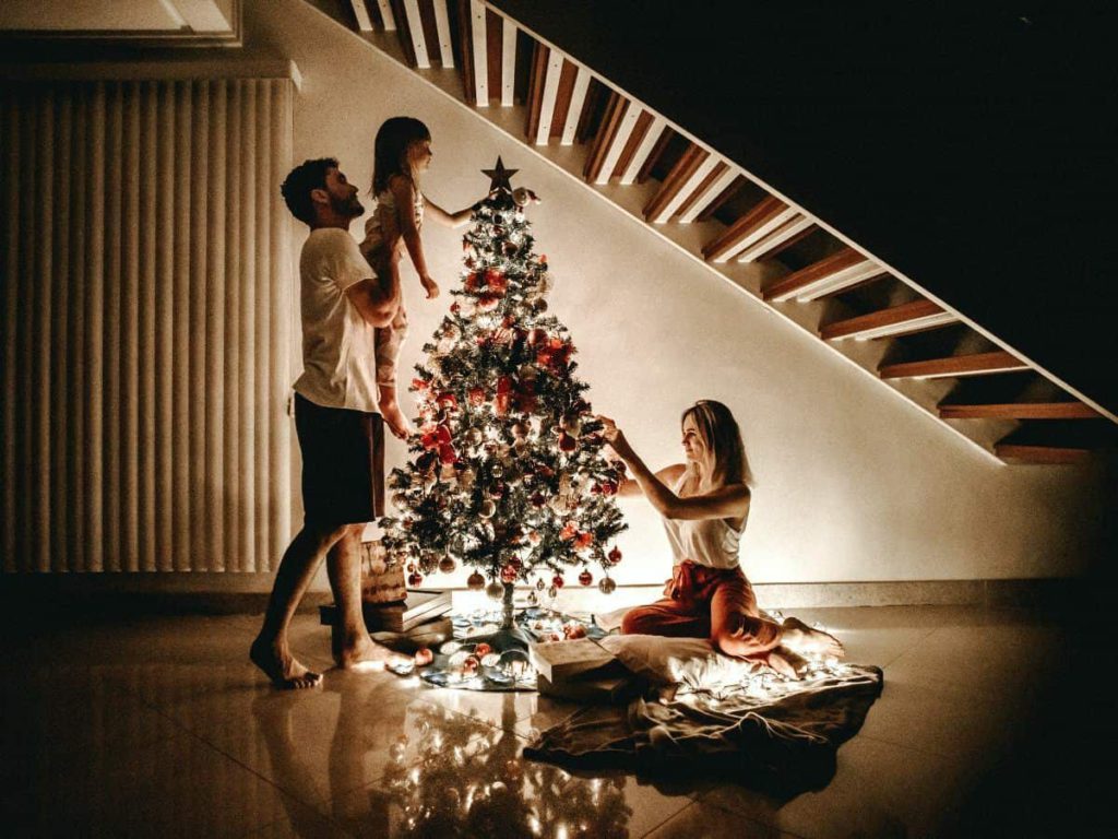 family setting up christmas tree in a darker room