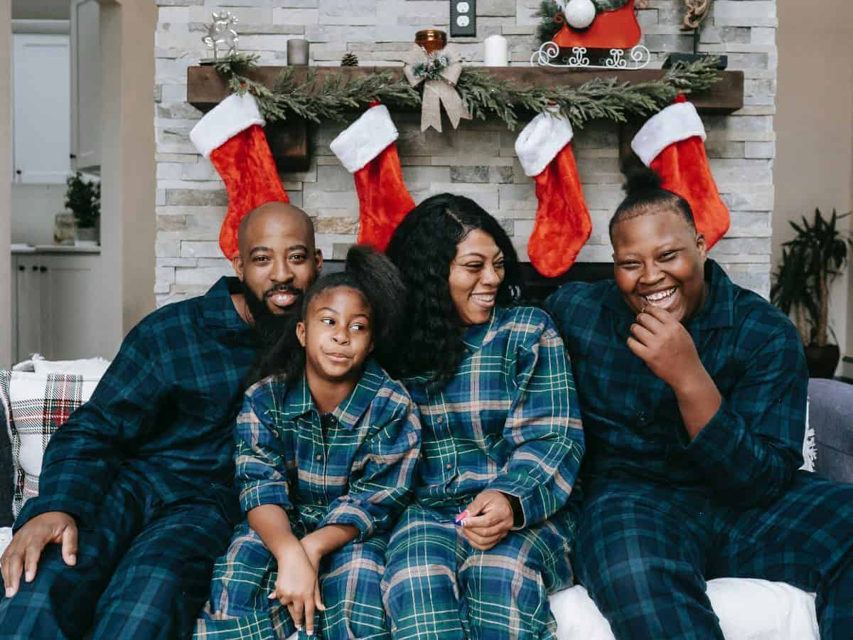 family of four sitting in front of a fireplace at christmas