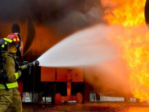 one firefighter using a water hose to fight a fire