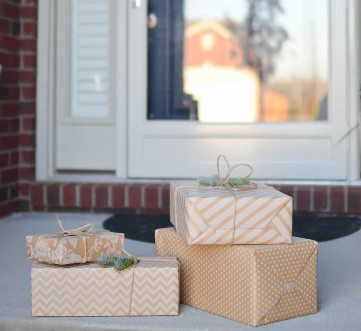 Four packages wrapped in light brown paper are sitting by the front door of a home.