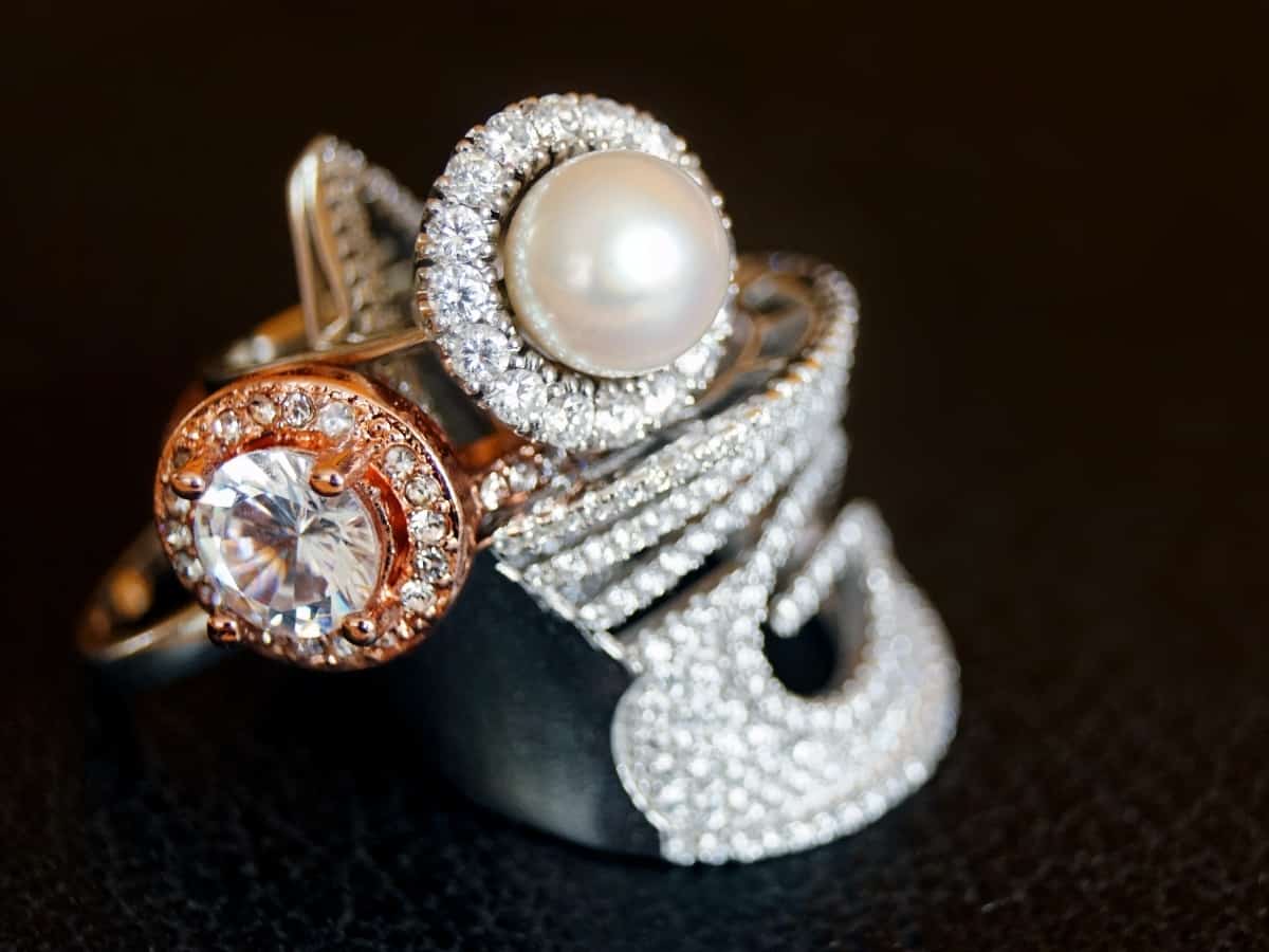 closeup of three rings, one with pearl, others with diamonds